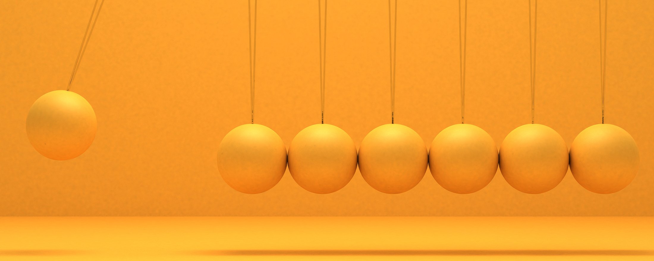 Newton’s cradle with six orange spheres; one sphere is raised, ready to swing.