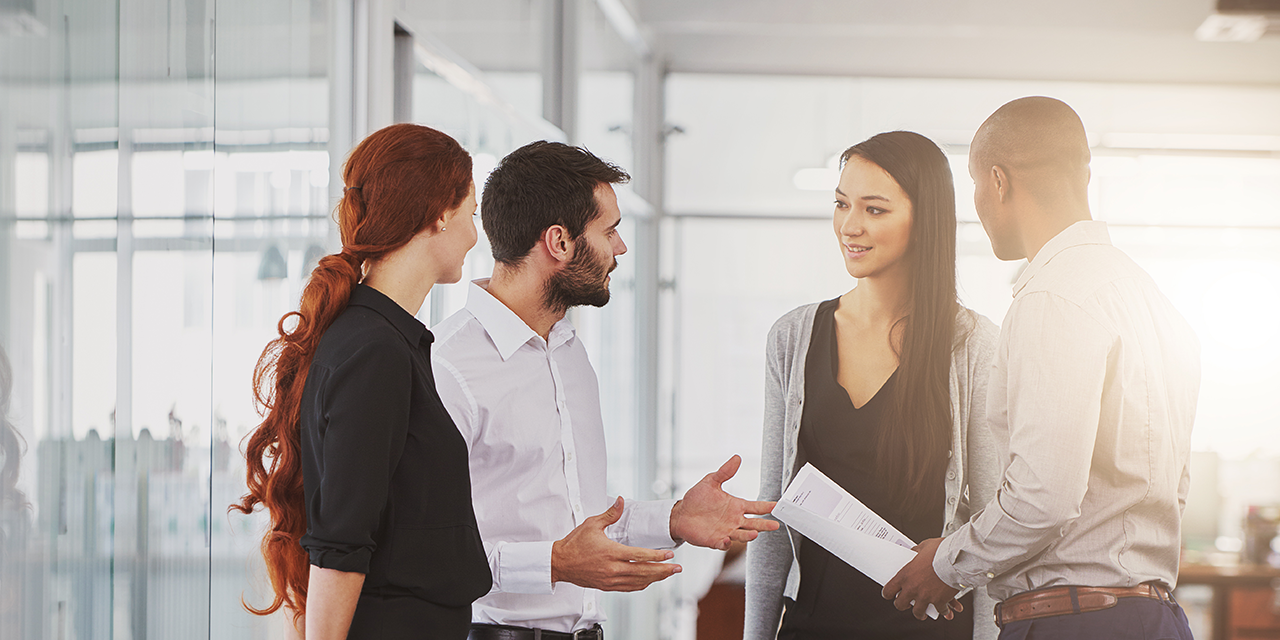 Group of young professionals networking in an office building hallway