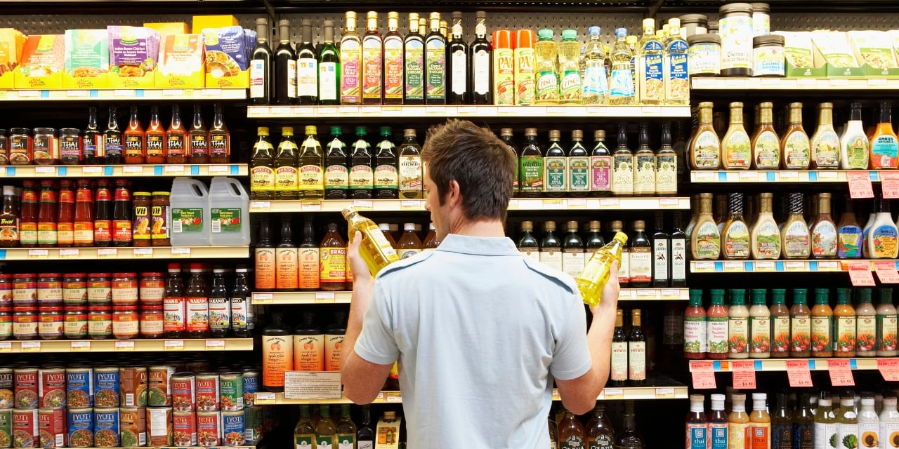Man looking at bottles of oil at a grocery store.