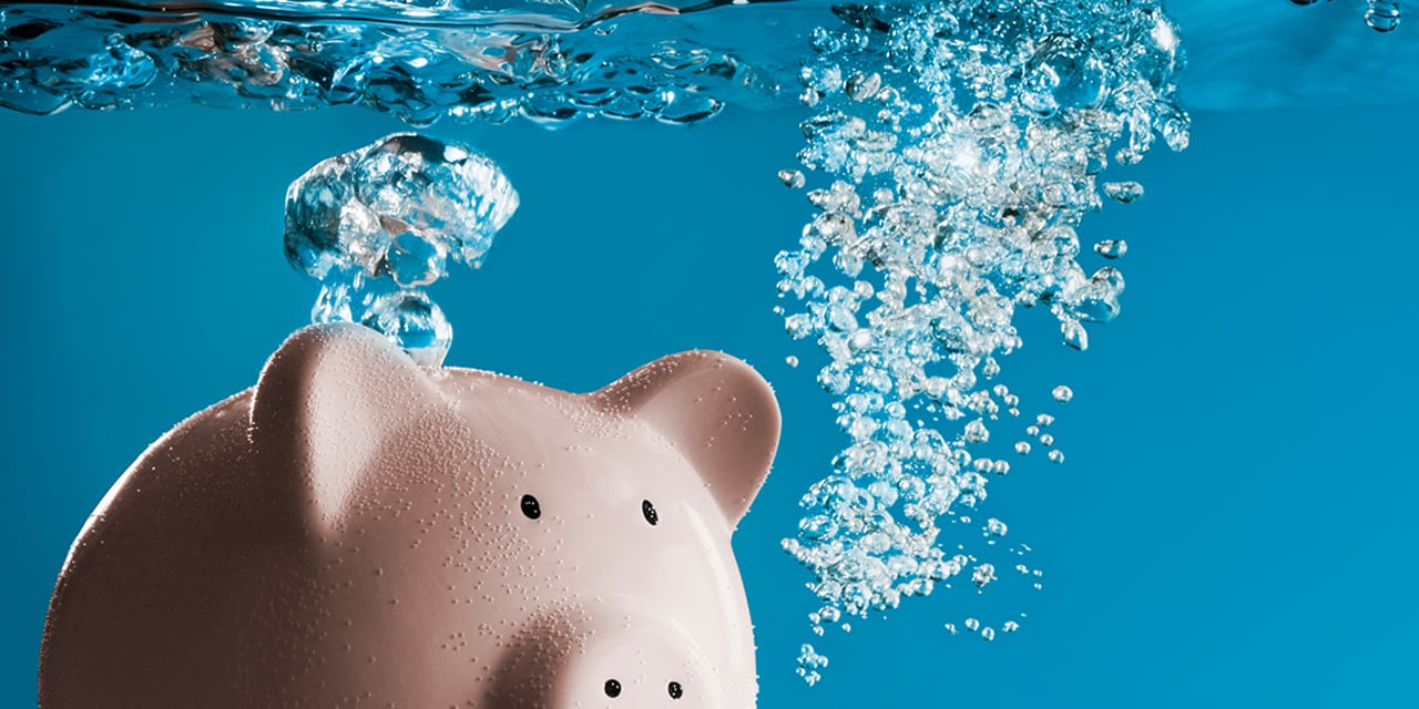 Pink ceramic piggy bank sinking under water.